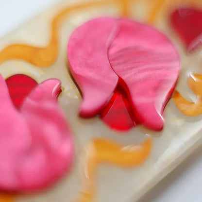 Close-up detail of the pink resin flower on an Erstwilder 'Flower and Thorn' brooch.