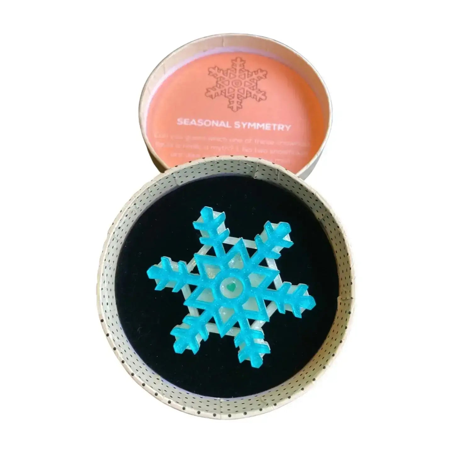 Blue snowflake design on a black background with 'Seasonal Symmetry' text on a pink container.